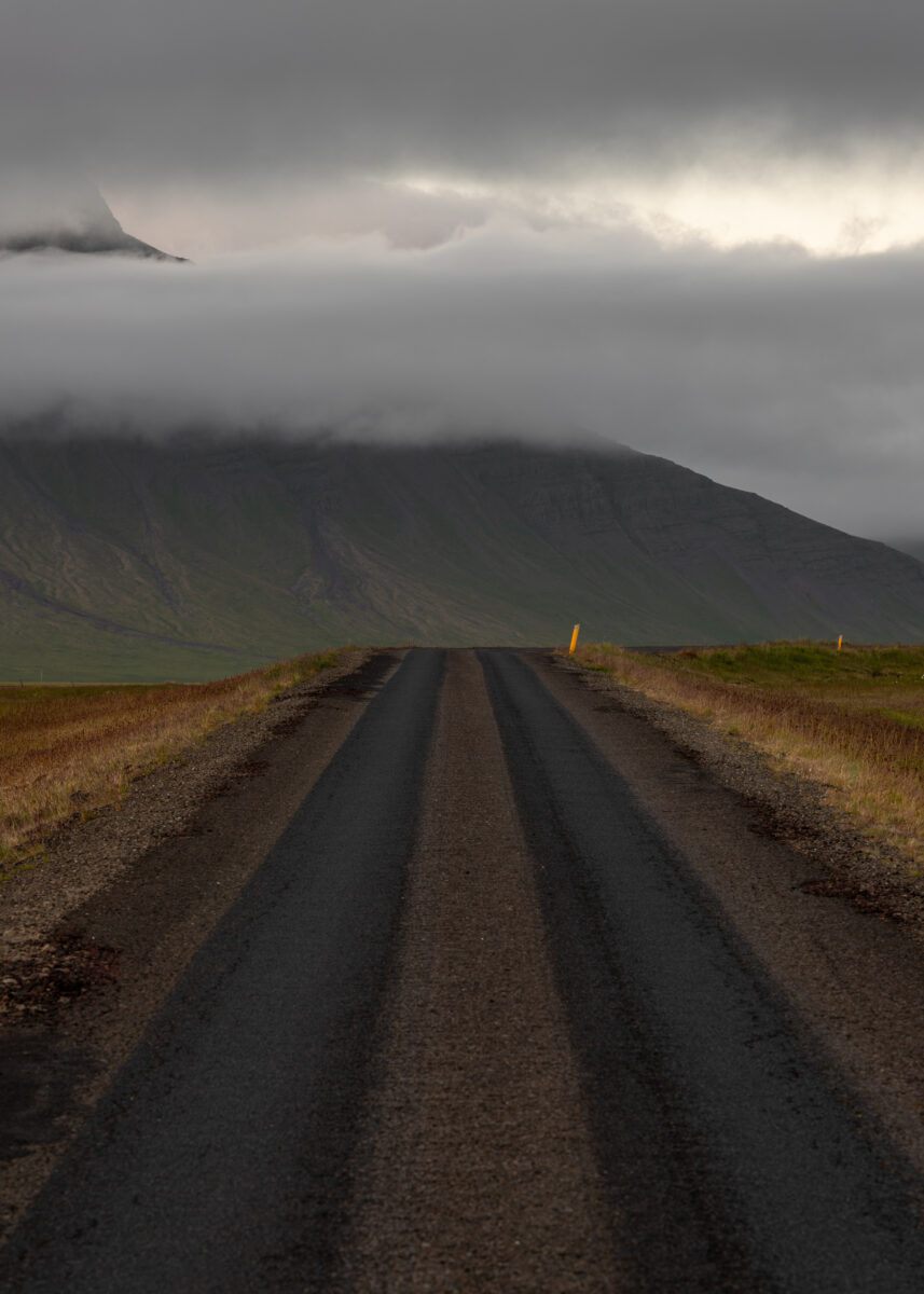 Black gravel road in Iceland. Mountains in the background.