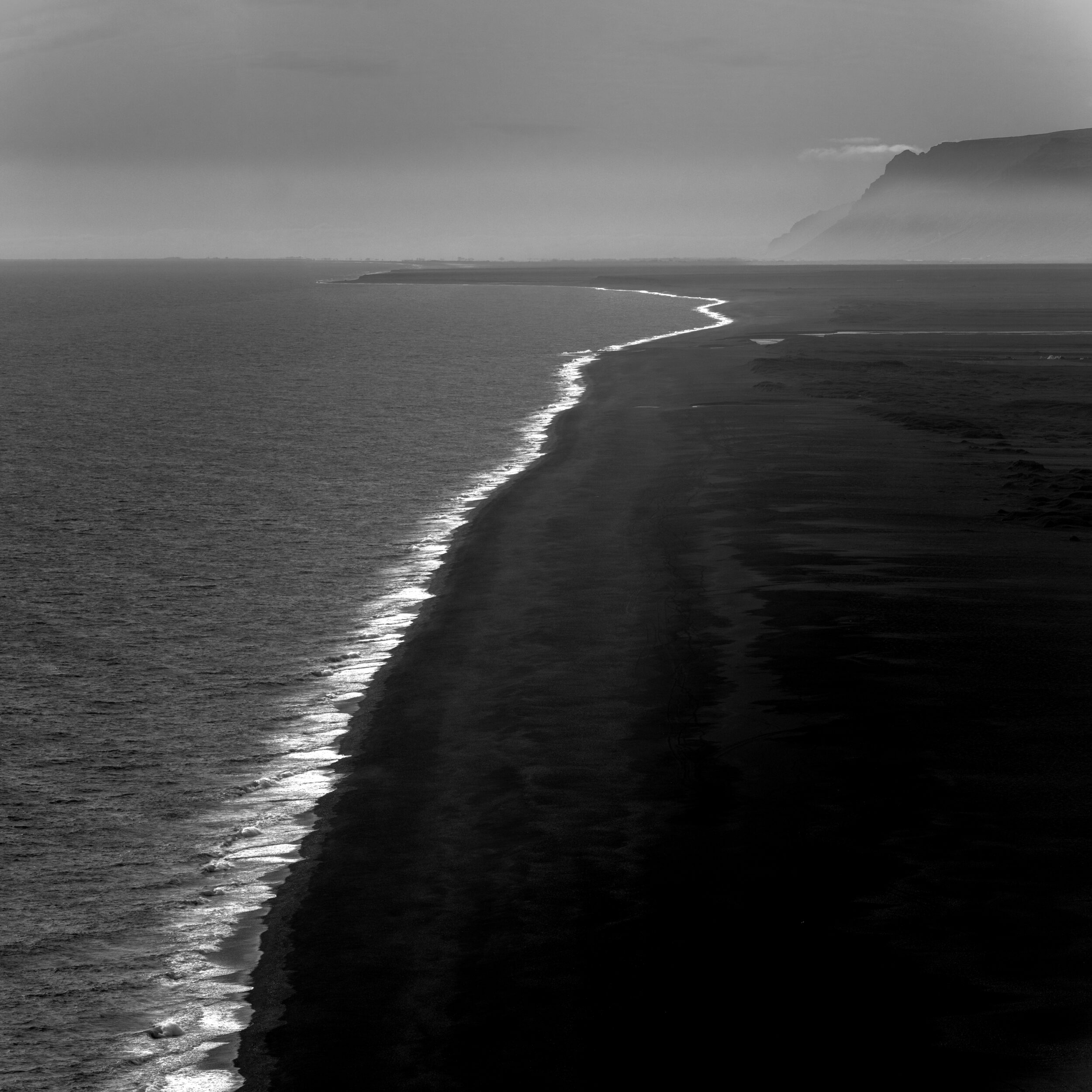 Black sand beach impression with waves crushing the coast